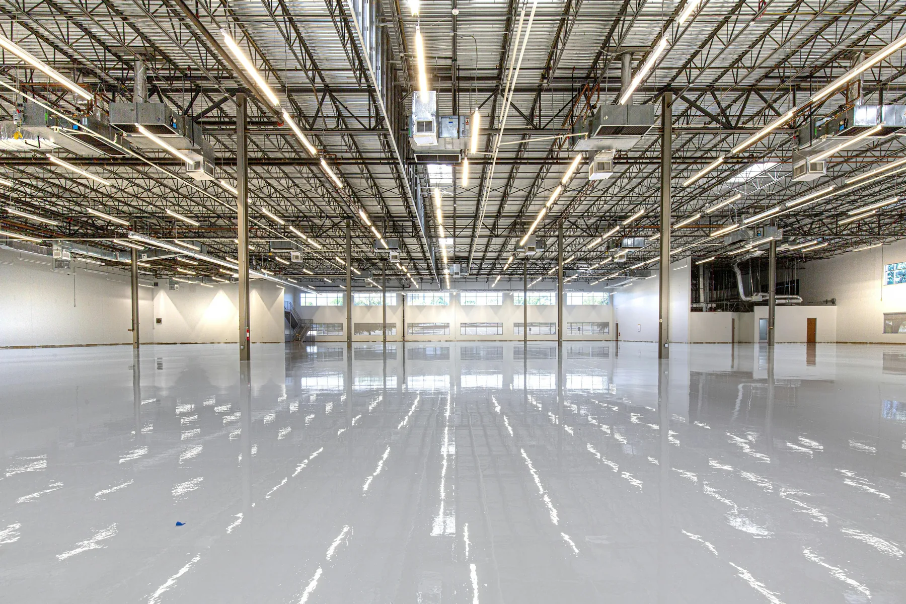 Spacious commercial facility interior with a glossy gray epoxy-coated floor and overhead lighting