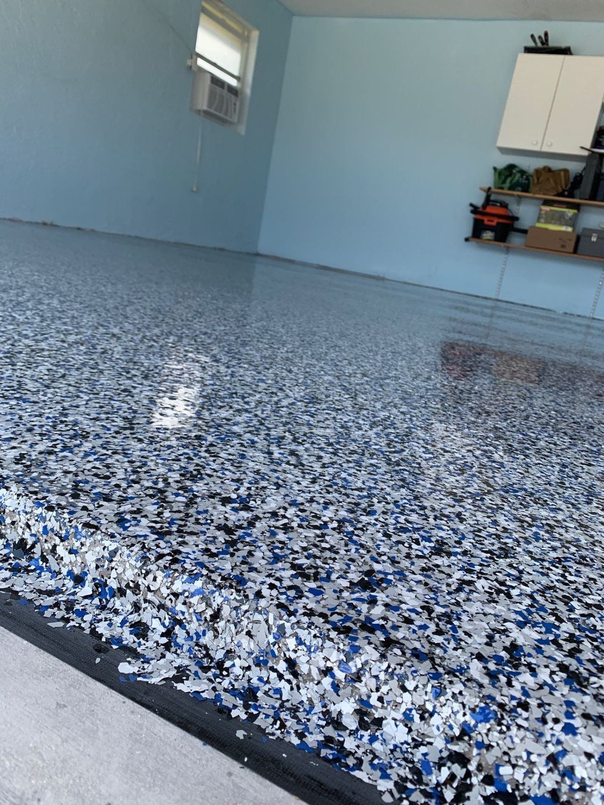 Gray and black flake epoxy floor with a coved base running up the wall