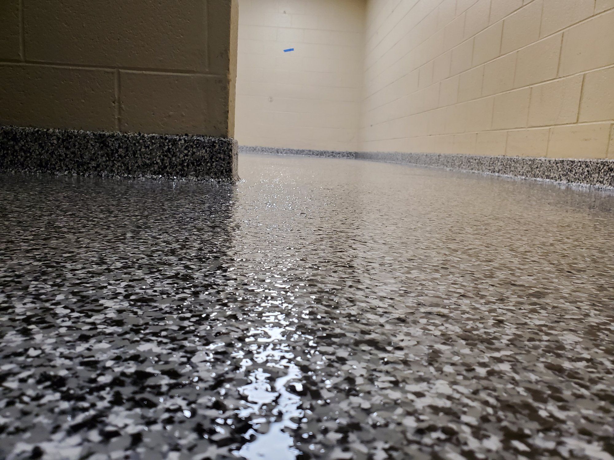 Tan and gray flake epoxy floor with a glossy topcoat and an integral cove base