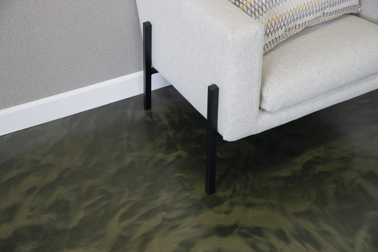 Dark green metallic pigment floor coating beside a modern chair